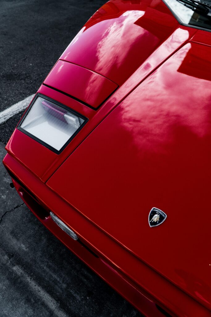 High-angle shot of red Lamborghini hood highlighting emblem and glossy finish.